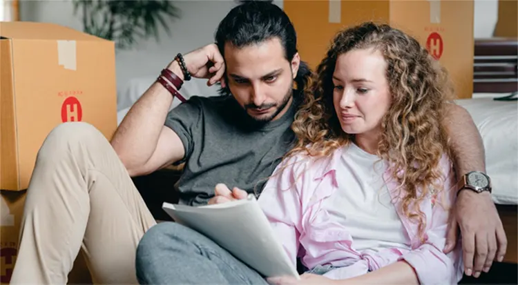 
Thoughtful couple writing in notebook while moving house 