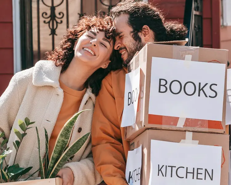 
Two happy people carrying boxes and plants