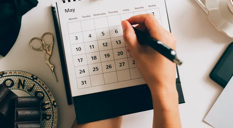 
A person writing on a desk calendar